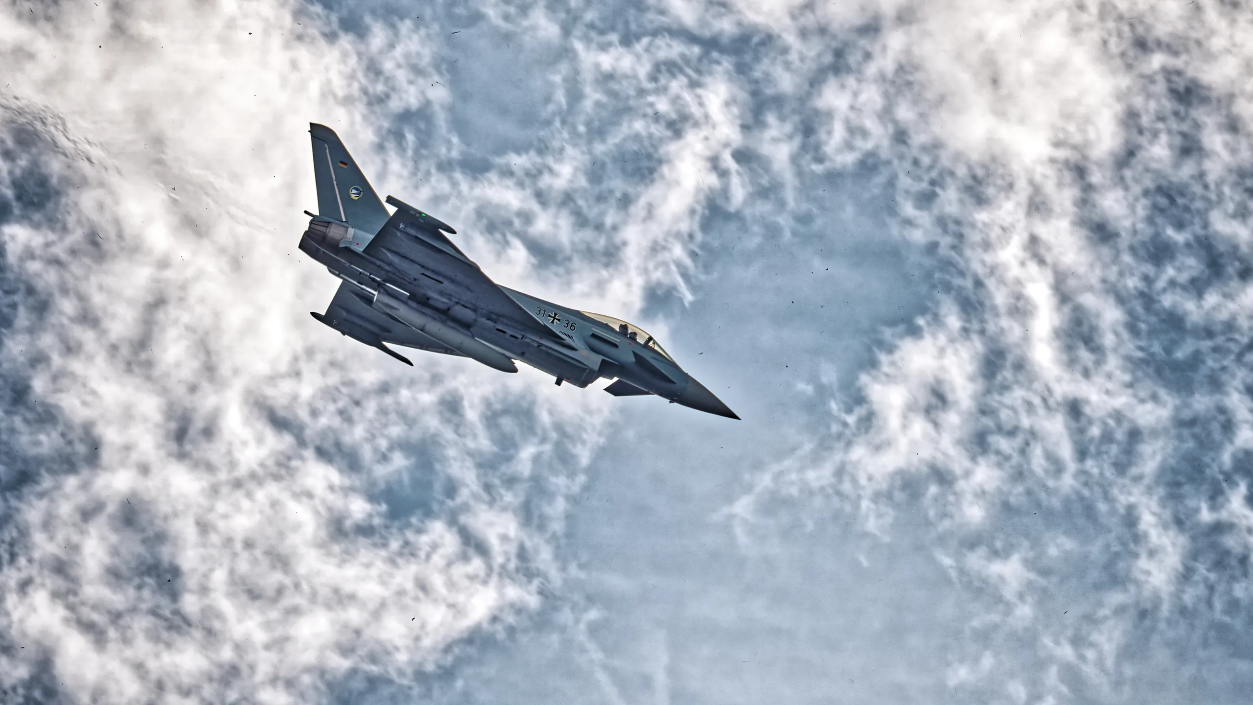 Eurofighter Typhoon der deutschen Luftwaffe mit der Kennung 31+36 im dynamischen Flug vor einer eindrucksvollen Wolkenkulisse.