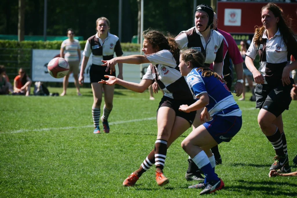 Damenrugby-Spielerin des FC St. Pauli passt den Rugbyball während eines Angriffs an einer Gegenspielerin von Bayern München vorbei.
