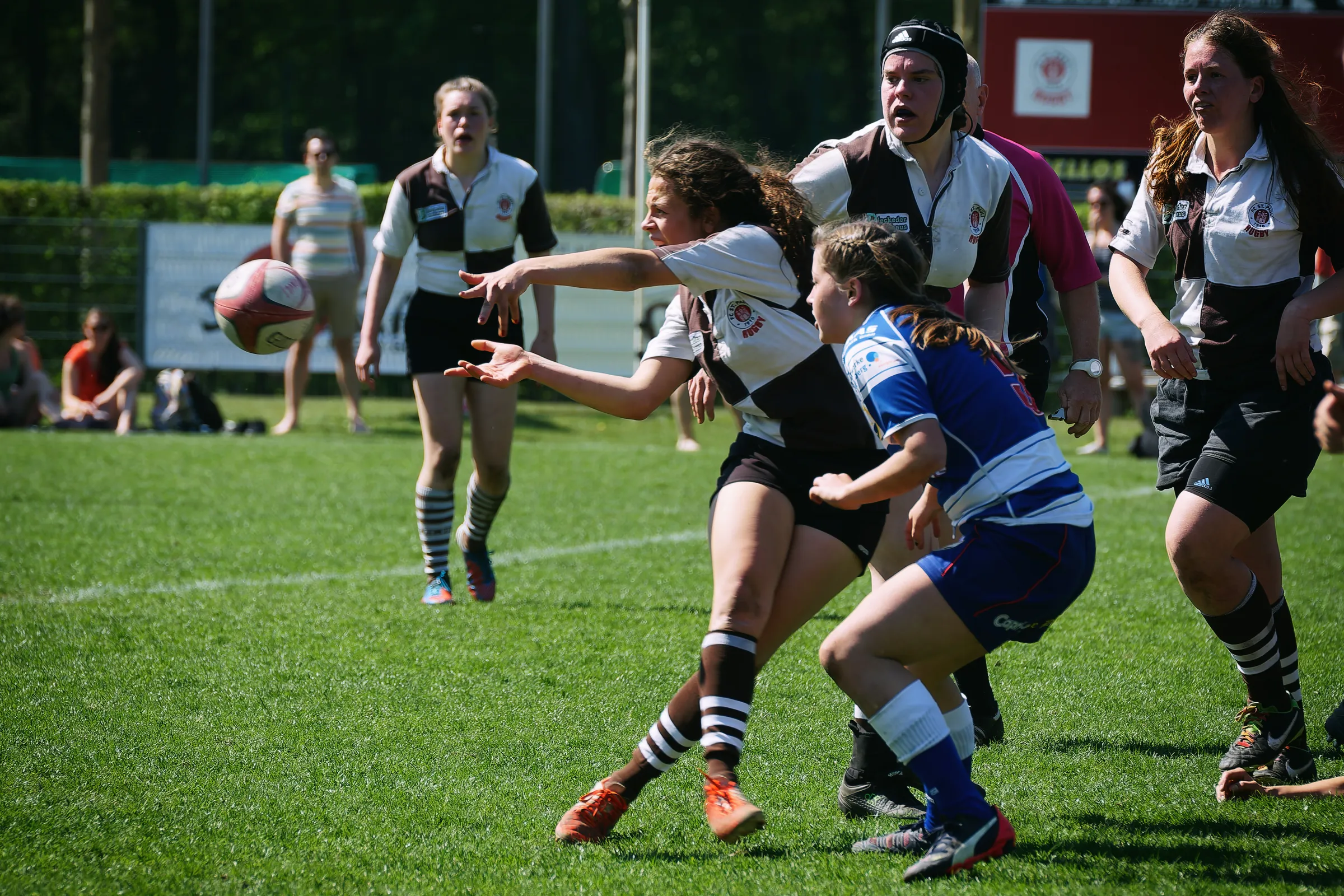 Damenrugby-Spielerin des FC St. Pauli passt den Rugbyball während eines Angriffs an einer Gegenspielerin von Bayern München vorbei.