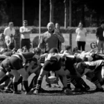 Schwarz-Weiß-Aufnahme eines intensiven Gedränges beim Damenrugby zwischen dem FC St. Pauli und Bayern München mit zahlreichen Spielerinnen und einem Schiedsrichter im Hintergrund.
