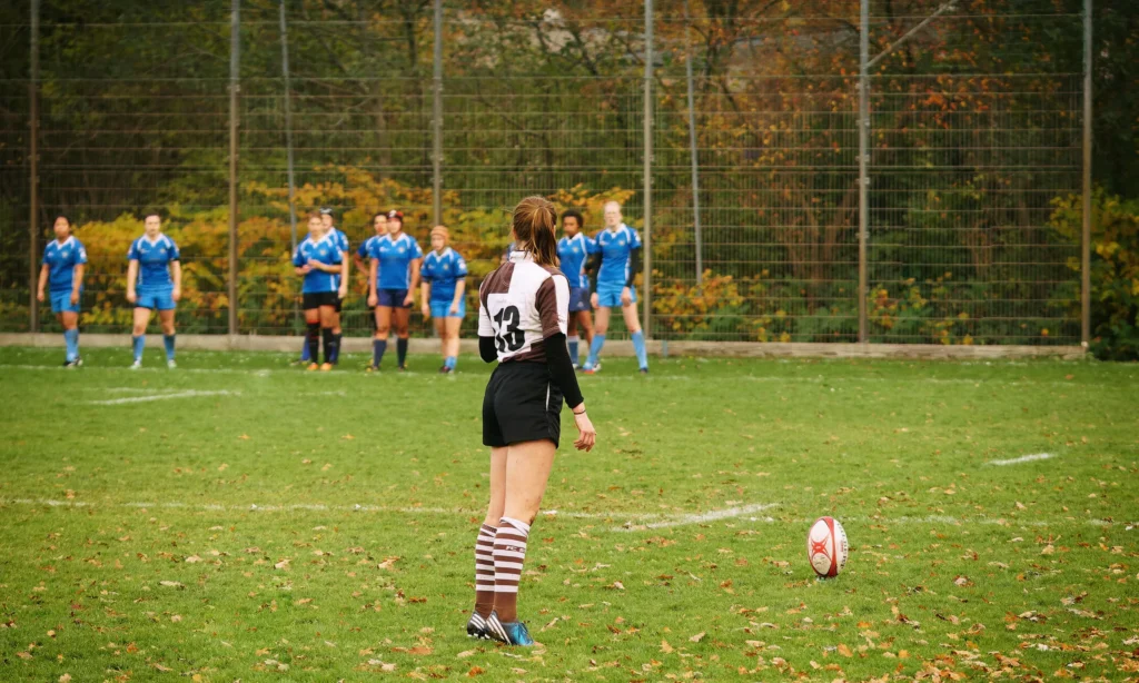 Damenrugby-Spielerin des FC St. Pauli mit der Rückennummer 13 steht vor einem ruhenden Rugbyball und bereitet einen Kick gegen Bayern München vor.