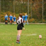 Damenrugby-Spielerin des FC St. Pauli mit der Rückennummer 13 steht vor einem ruhenden Rugbyball und bereitet einen Kick gegen Bayern München vor.