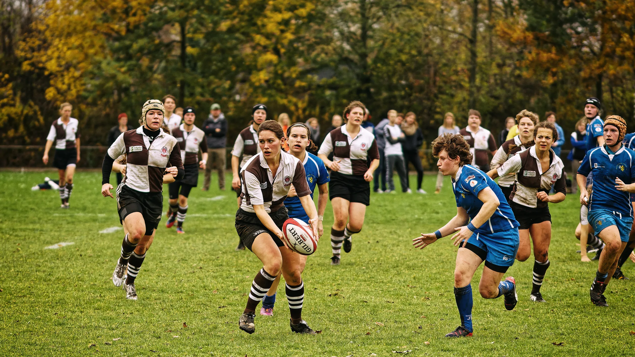 Mehrere Rugbyspielerinnen des FC St. Pauli und Bayern München verfolgen eine Spielerin von St. Pauli mit dem Ball während eines schnellen Angriffs.