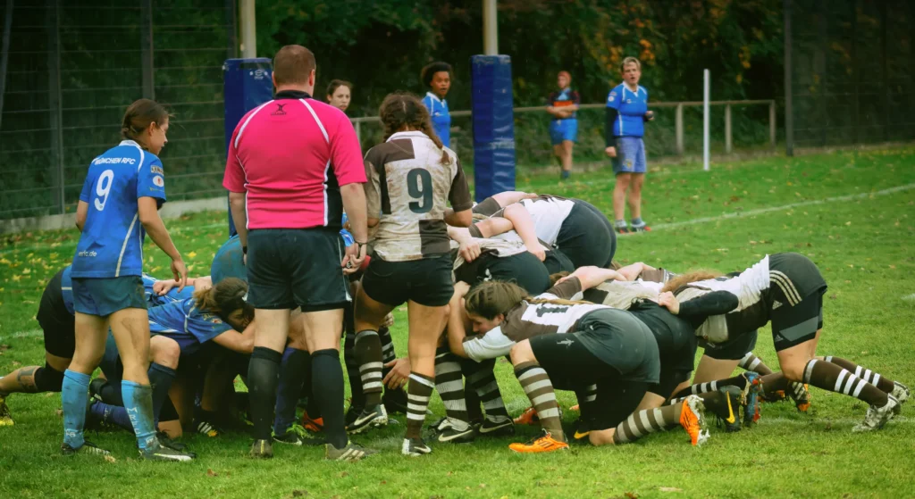 Intensives Gedränge beim Damenrugby zwischen dem FC St. Pauli in Braun-Weiß und Bayern München in Blau-Weiß, während der Schiedsrichter das Spiel beobachtet
