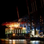 Großes Containerschiff HMM St. Petersburg am beleuchteten Containerterminal Burchardkai im Hamburger Hafen bei Nacht.