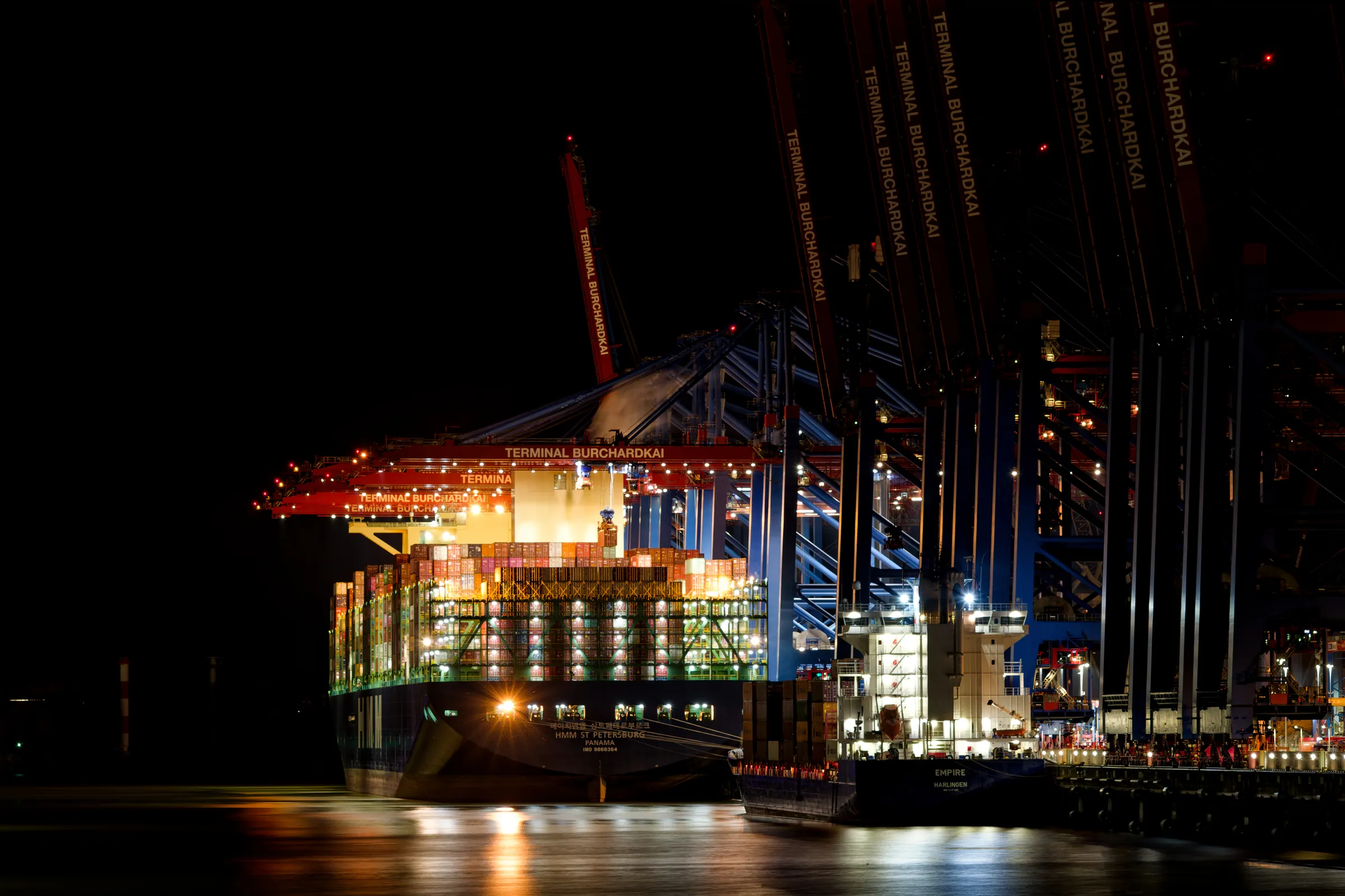 Großes Containerschiff HMM St. Petersburg am beleuchteten Containerterminal Burchardkai im Hamburger Hafen bei Nacht.