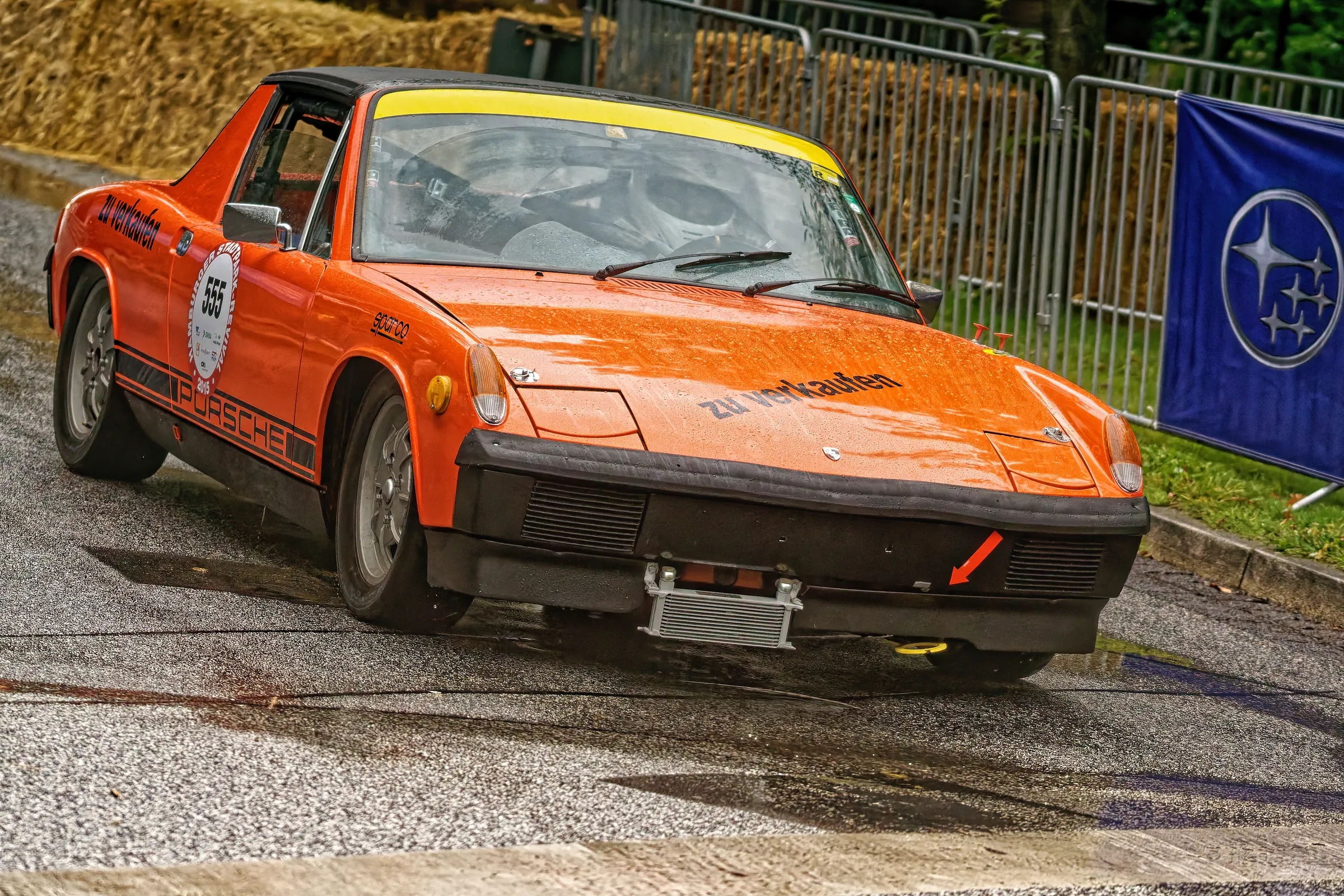 Orangefarbener Porsche 914 mit schwarzem Targadach und Startnummer 555 in einer Kurve beim Hamburger Stadtpark-Revival.