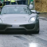 Grauer Porsche 918 Spyder mit eingeschalteten LED-Scheinwerfern auf regennasser Strecke beim Hamburger Stadtpark-Revival. Grauer Porsche 918 Spyder mit eingeschalteten LED-Scheinwerfern auf regennasser Strecke beim Hamburger Stadtpark-Revival.