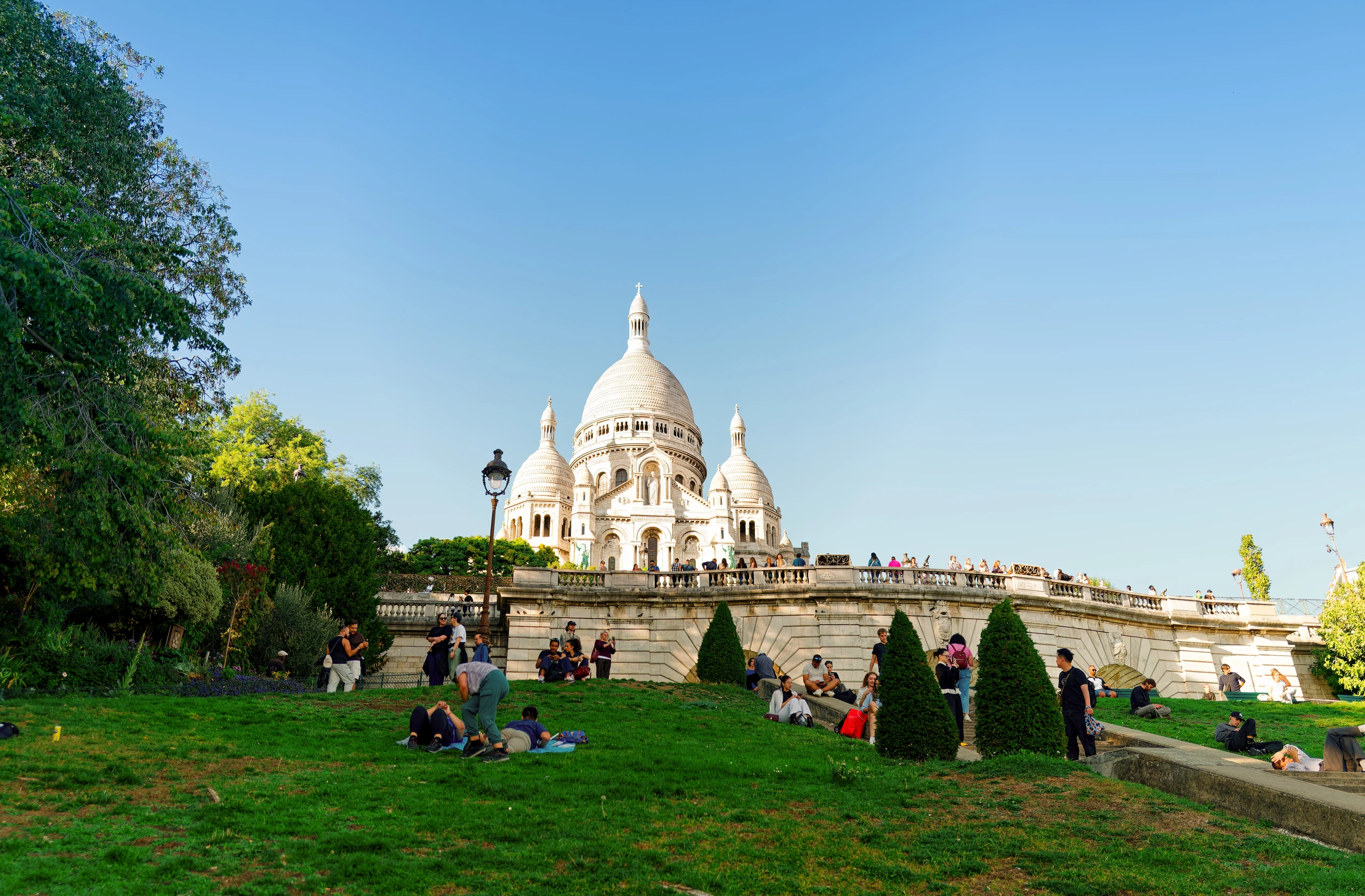 Basilika Sacré-Cœur auf dem Montmartre mit grüner Wiese und Besuchern