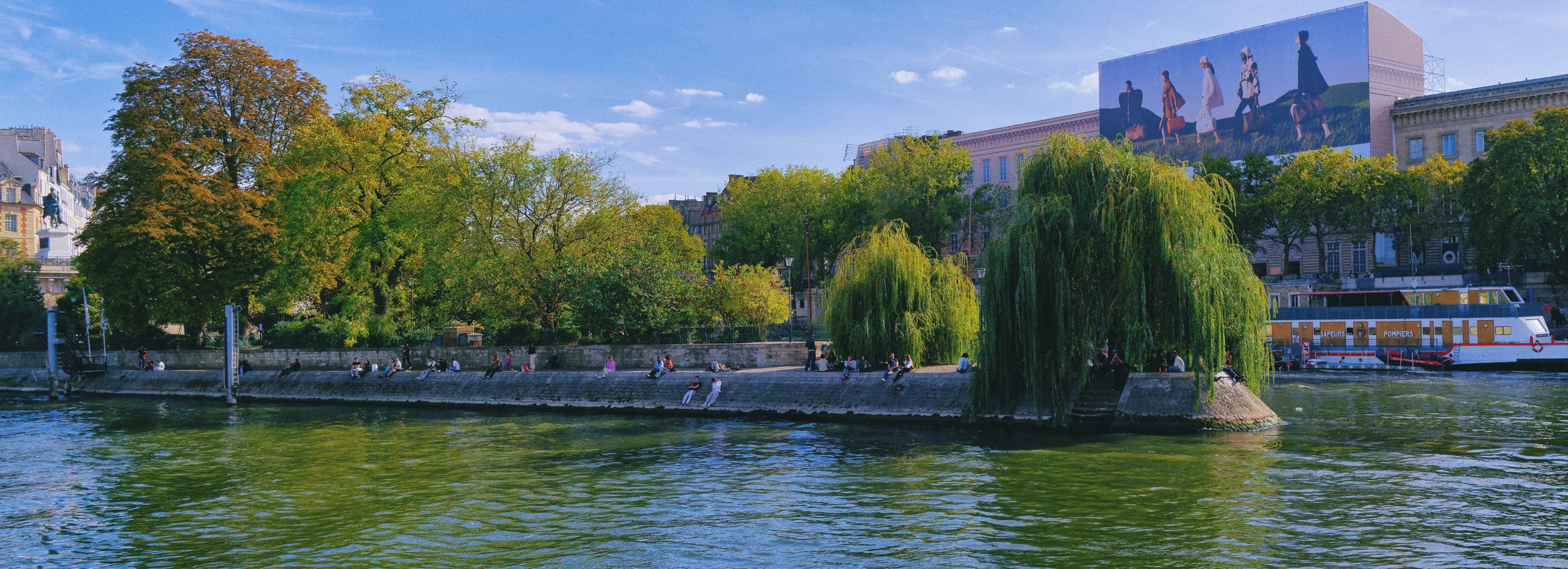 Pariser Stadtleben am Ufer der Seine mit Bäumen und Menschen am Wasser