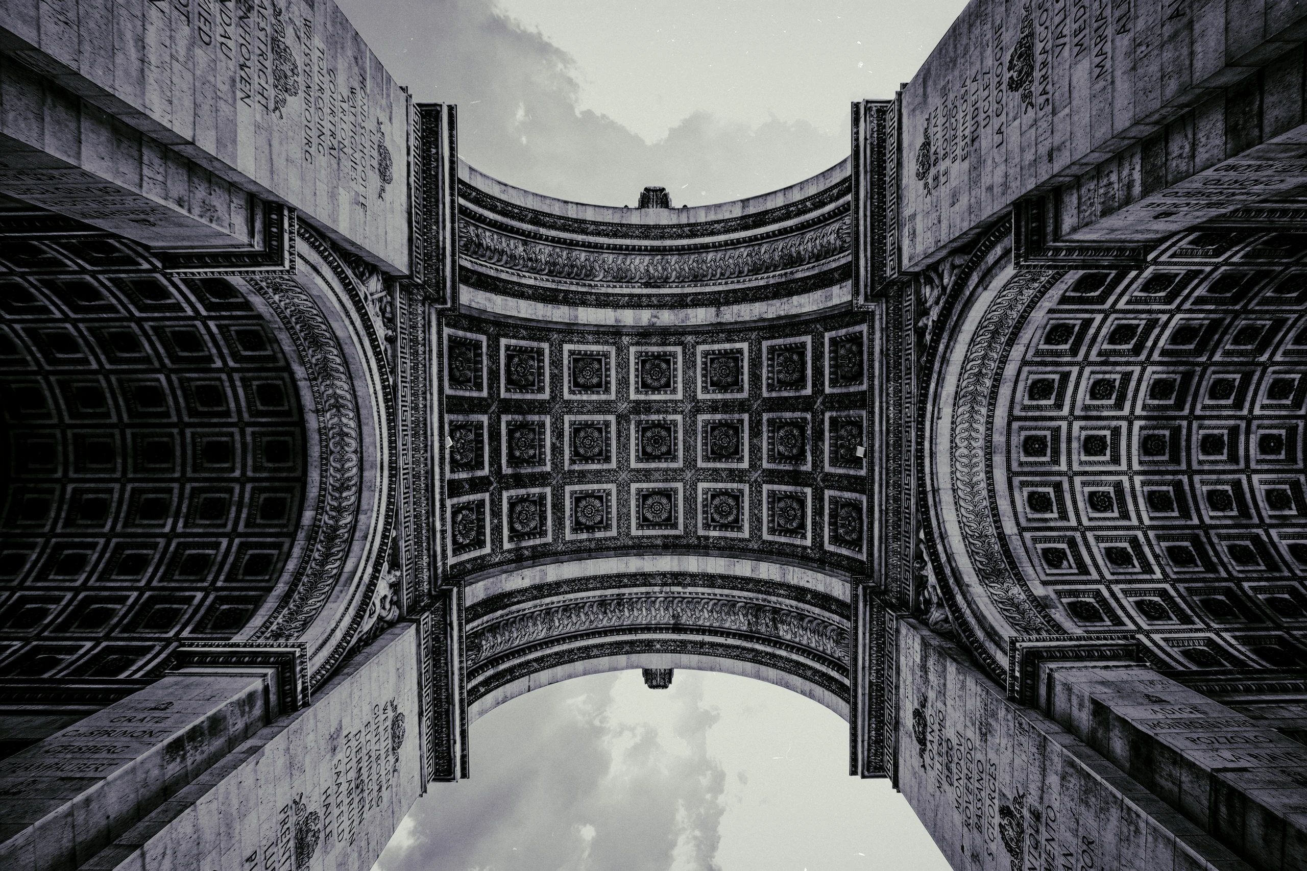 Schwarz-Weiß-Aufnahme der kunstvoll verzierten Unterseite des Arc de Triomphe